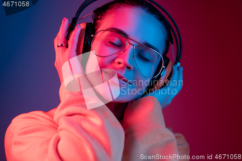 Image of Fashion pretty woman with headphones listening to music over neon background