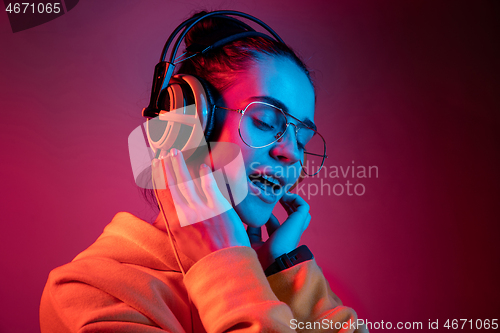 Image of Fashion pretty woman with headphones listening to music over neon background