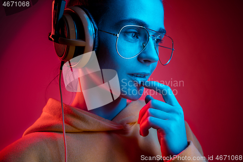 Image of Fashion pretty woman with headphones listening to music over neon background