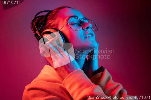 Image of Fashion pretty woman with headphones listening to music over neon background