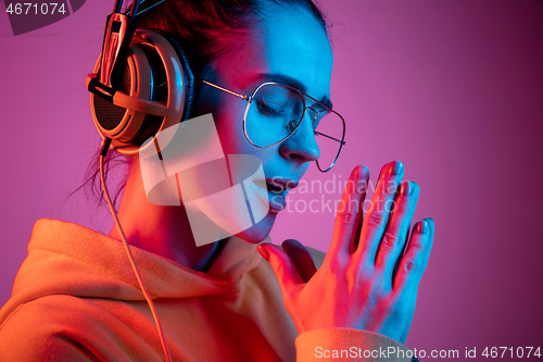 Image of Fashion pretty woman with headphones listening to music over neon background