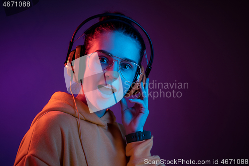 Image of Fashion pretty woman with headphones listening to music over neon background