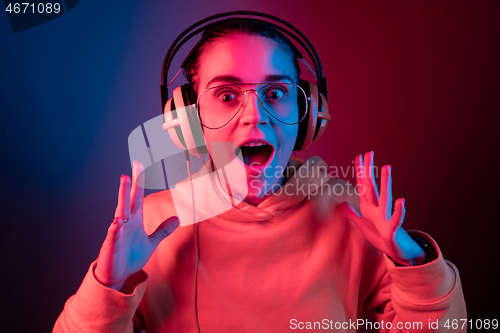 Image of Fashion pretty woman with headphones listening to music over neon background