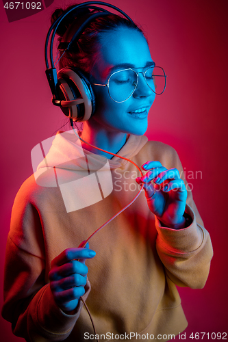 Image of Fashion pretty woman with headphones listening to music over neon background