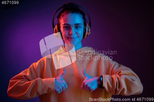 Image of Fashion pretty woman with headphones listening to music over neon background