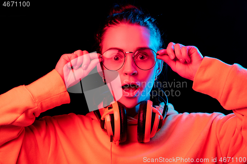 Image of Fashion pretty woman with headphones listening to music over neon background