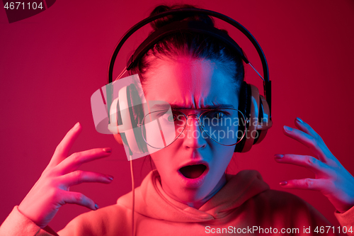 Image of Fashion pretty woman with headphones listening to music over neon background