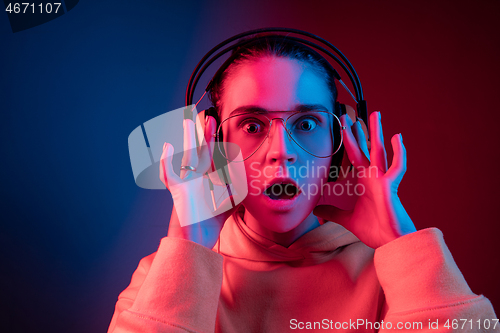 Image of Fashion pretty woman with headphones listening to music over neon background