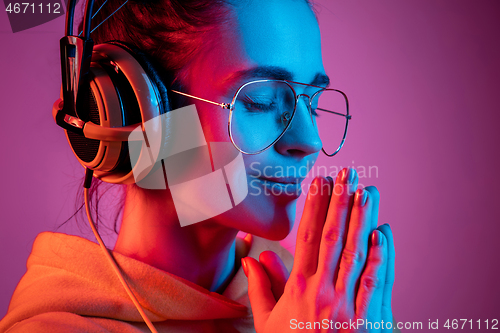 Image of Fashion pretty woman with headphones listening to music over neon background