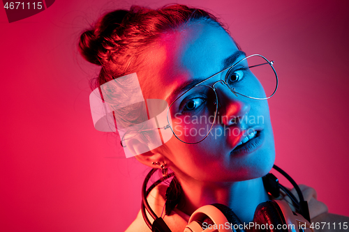 Image of Fashion pretty woman with headphones listening to music over neon background