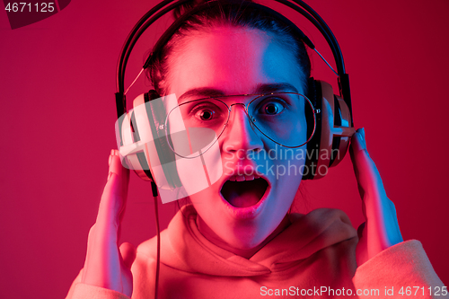 Image of Fashion pretty woman with headphones listening to music over neon background