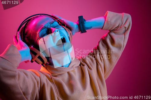 Image of Fashion pretty woman with headphones listening to music over neon background