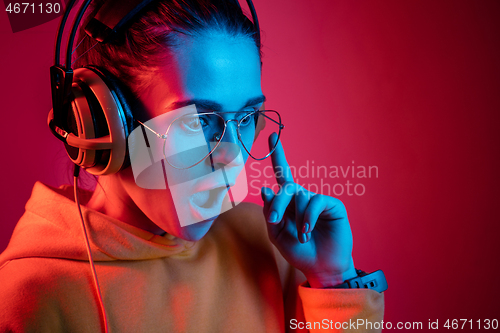 Image of Fashion pretty woman with headphones listening to music over neon background