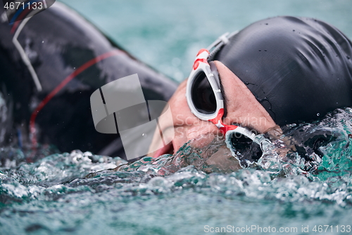 Image of triathlon athlete swimming on lake wearing wetsuit