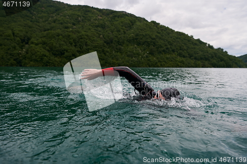 Image of triathlon athlete swimming on lake wearing wetsuit