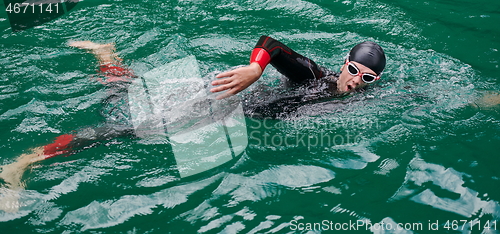 Image of triathlon athlete swimming on lake wearing wetsuit