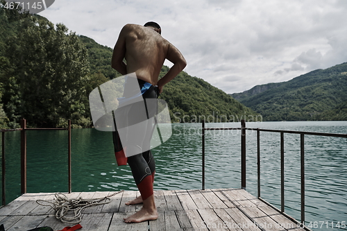 Image of triathlon athlete getting ready for swimming training on lake