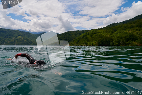 Image of triathlon athlete swimming on lake wearing wetsuit