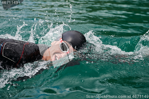 Image of triathlon athlete swimming on lake wearing wetsuit