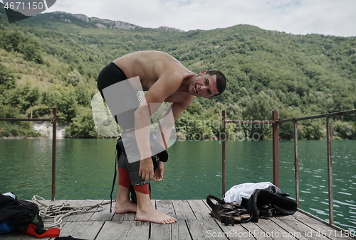 Image of triathlon athlete getting ready for swimming training on lake