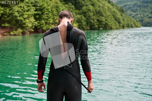 Image of triathlon athlete getting ready for swimming training on lake