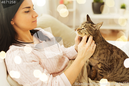 Image of close up of woman with tabby cat in bed at home