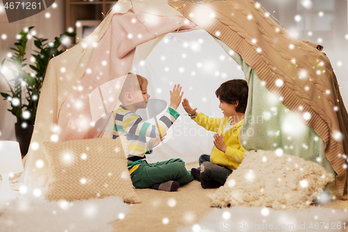 Image of boys playing clapping game in kids tent at home