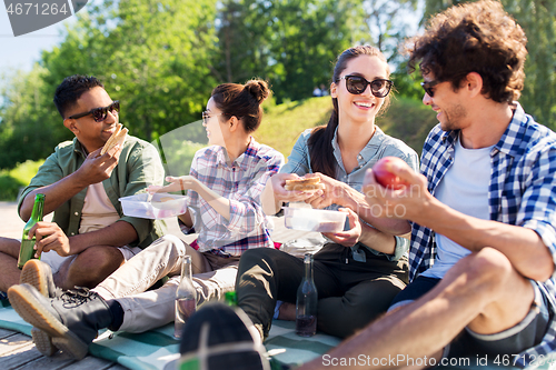 Image of happy friends having picnic at summer park