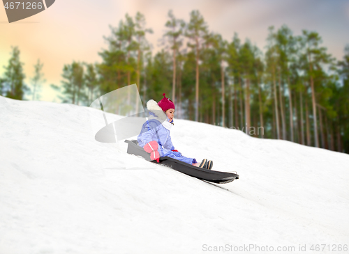 Image of happy little girl sliding down on sled in winter