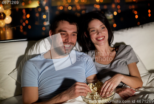 Image of couple with popcorn watching tv at night at home