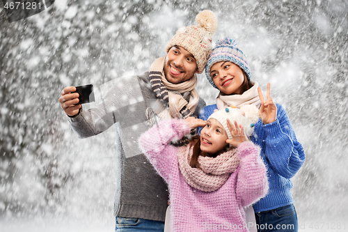 Image of happy family taking selfie by smartphone over snow