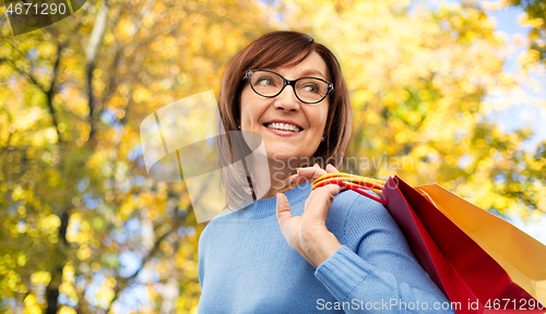 Image of senior woman with shopping bags over autumn park