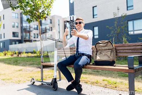 Image of businessman taking selfie and showing thumbs up