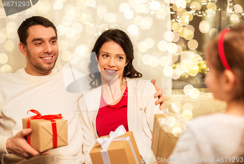 Image of happy family giving christmas presents at home