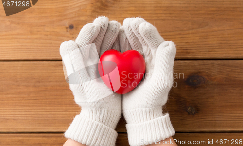 Image of hands in white woollen gloves holding red heart