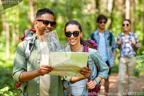 Image of friends with map and backpacks hiking in forest