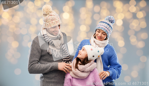 Image of family in winter clothes over christmas lights