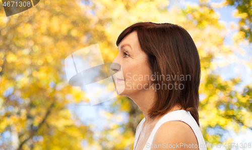 Image of profile of senior woman over autumn trees