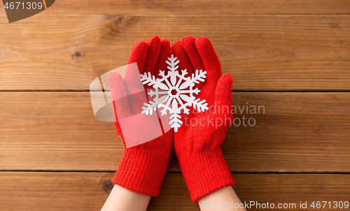 Image of hands in red woollen gloves holding big snowflake