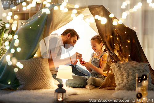 Image of family playing tea party in kids tent at home