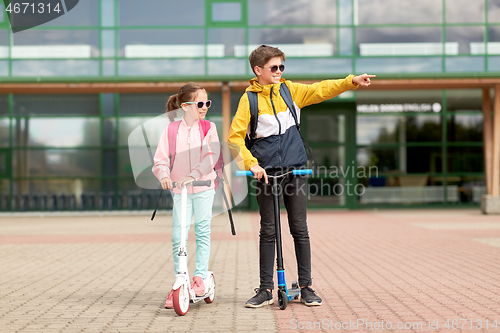 Image of happy school children with backpacks and scooters