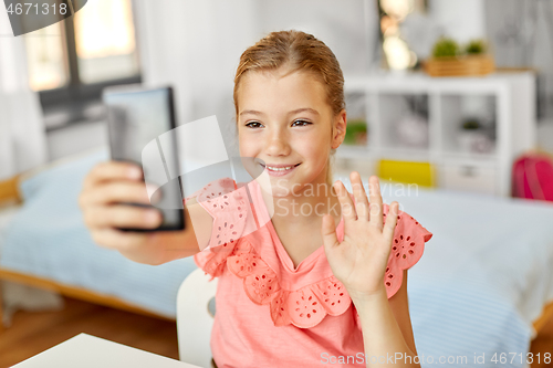 Image of happy girl with smartphone taking selfie at home