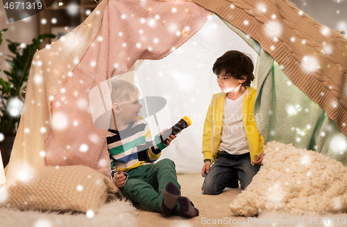 Image of happy boys with torch light in kids tent at home