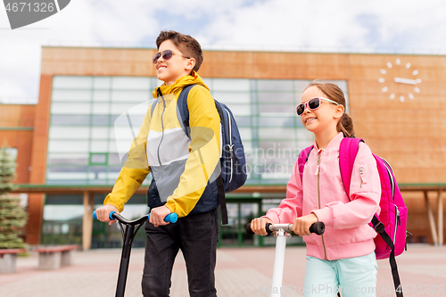 Image of school children with backpacks riding scooters