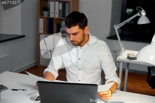 Image of businessman with papers working at night office