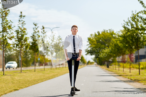 Image of young businessman riding electric scooter outdoors