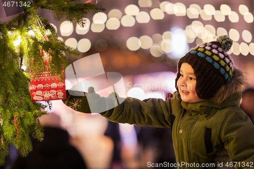 Image of boy reaching to gift bag hanging on christmas tree