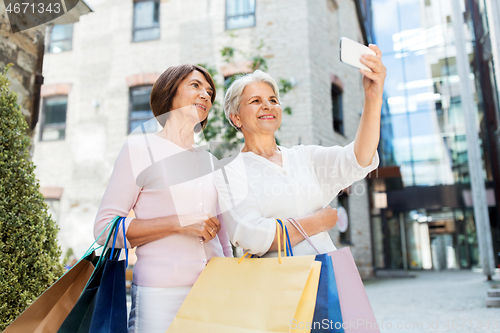 Image of old women with shopping bags taking selfie in city