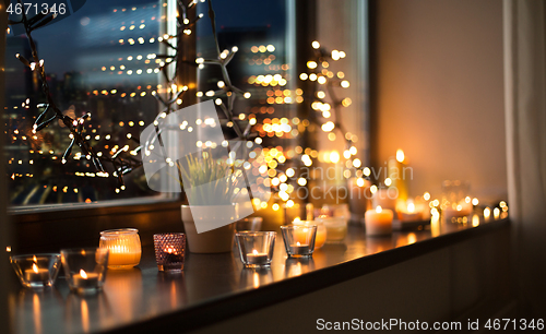 Image of candles burning on window sill with garland lights