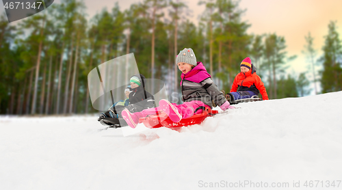 Image of kids sliding on sleds down snow hill in winter